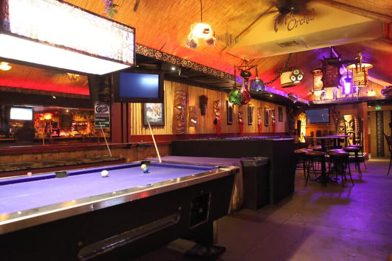A pool table set up in a games room, cues racked and balls arranged ready for a game
